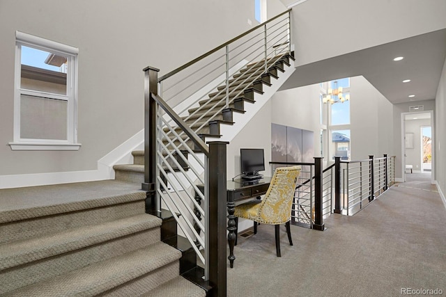 stairway with plenty of natural light, carpet, and an inviting chandelier