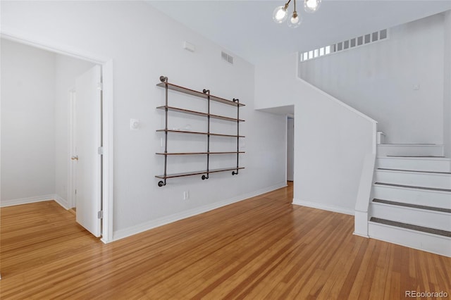 unfurnished living room featuring a chandelier and light wood-type flooring