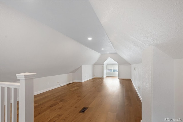 bonus room with hardwood / wood-style floors, lofted ceiling, and a textured ceiling