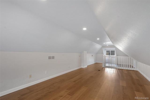 additional living space with lofted ceiling and hardwood / wood-style flooring