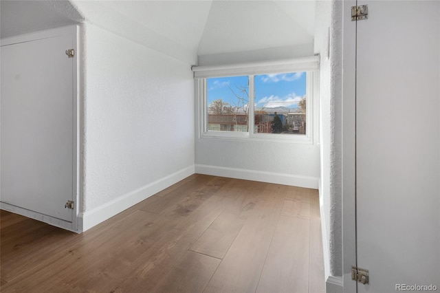 empty room with wood-type flooring and vaulted ceiling