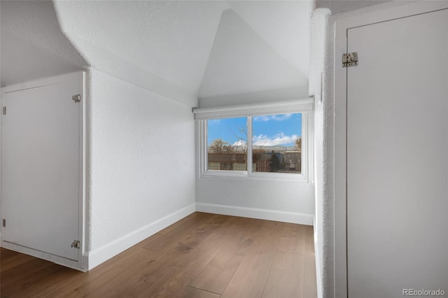 additional living space with hardwood / wood-style flooring and lofted ceiling