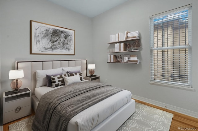 bedroom featuring wood finished floors, baseboards, and multiple windows