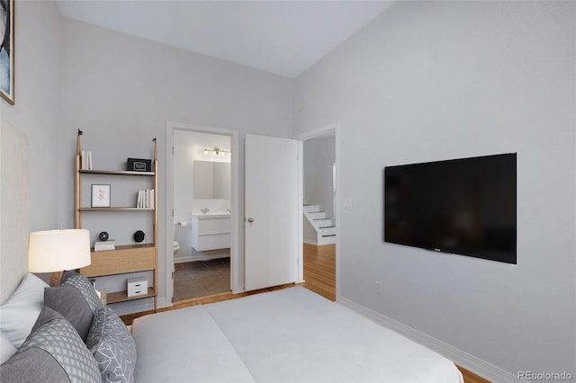 bedroom featuring wood finished floors, ensuite bath, and baseboards