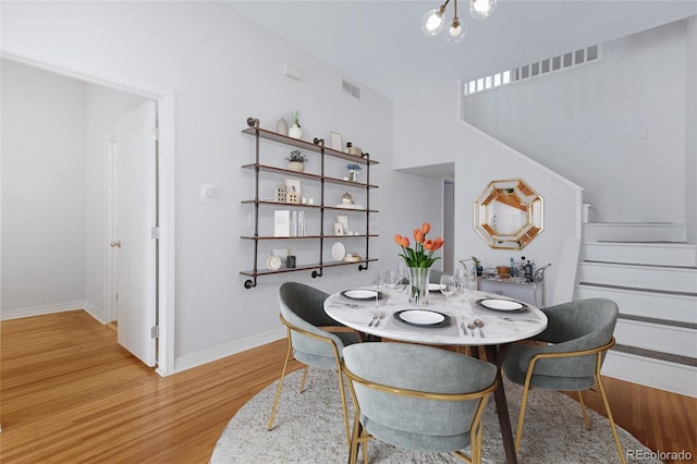 dining area with stairs, light wood-type flooring, and baseboards
