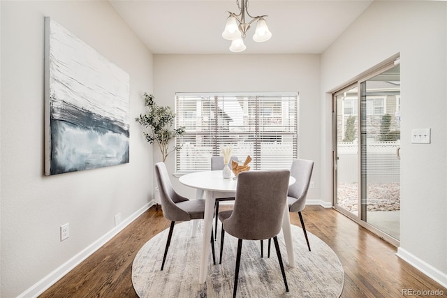 dining space with dark hardwood / wood-style flooring and a notable chandelier