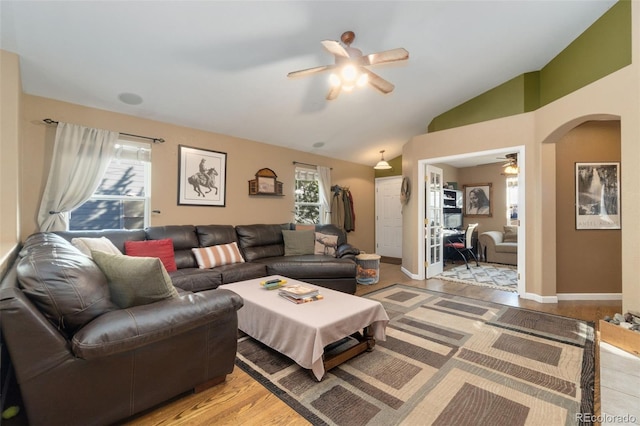 living room with ceiling fan, plenty of natural light, lofted ceiling, and light wood-type flooring