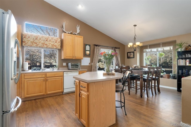 kitchen with dishwasher, vaulted ceiling, stainless steel fridge, light hardwood / wood-style floors, and a kitchen island