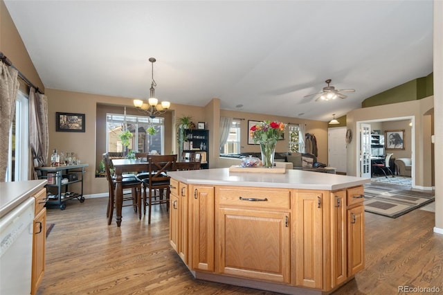 kitchen with white dishwasher, a kitchen island, light wood-type flooring, and vaulted ceiling