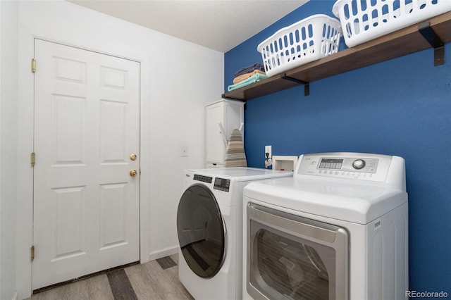 laundry area with light wood-type flooring and washing machine and clothes dryer