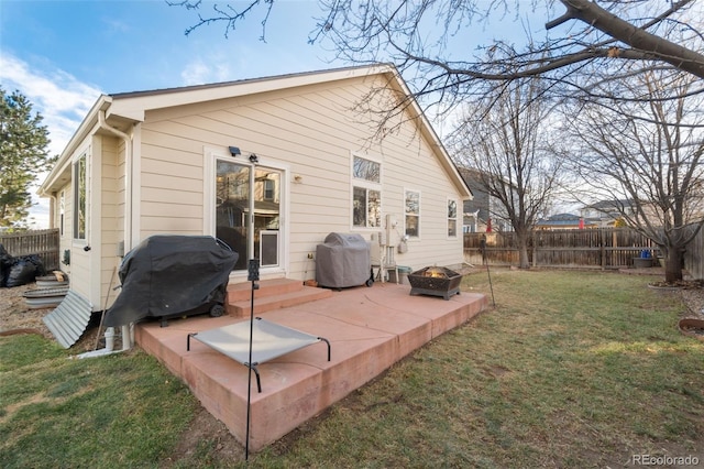 rear view of house featuring a yard, a patio, and an outdoor fire pit