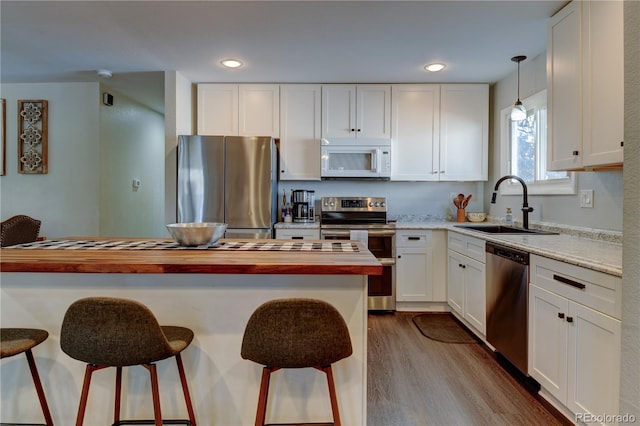 kitchen featuring appliances with stainless steel finishes, white cabinets, a sink, and a kitchen breakfast bar