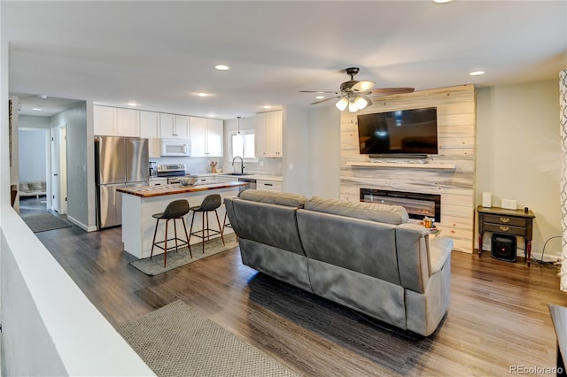 living room featuring a large fireplace, dark wood finished floors, and recessed lighting