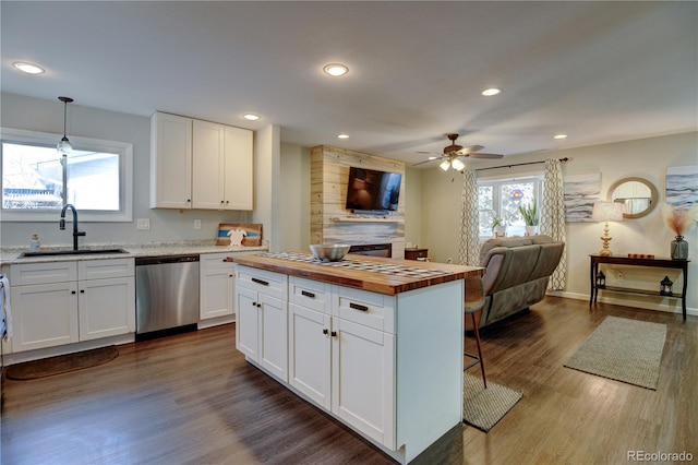 kitchen featuring butcher block counters, a sink, white cabinets, open floor plan, and stainless steel dishwasher