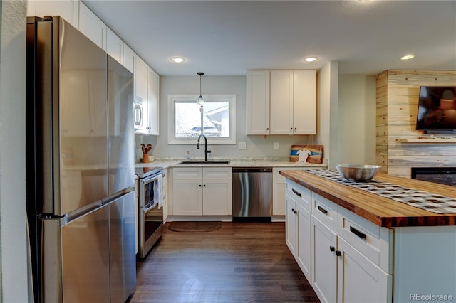 kitchen featuring stainless steel appliances, white cabinets, wooden counters, and a sink