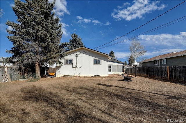 back of house featuring crawl space, a fenced backyard, and a fire pit