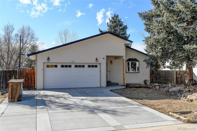 ranch-style house featuring concrete driveway, an attached garage, and fence