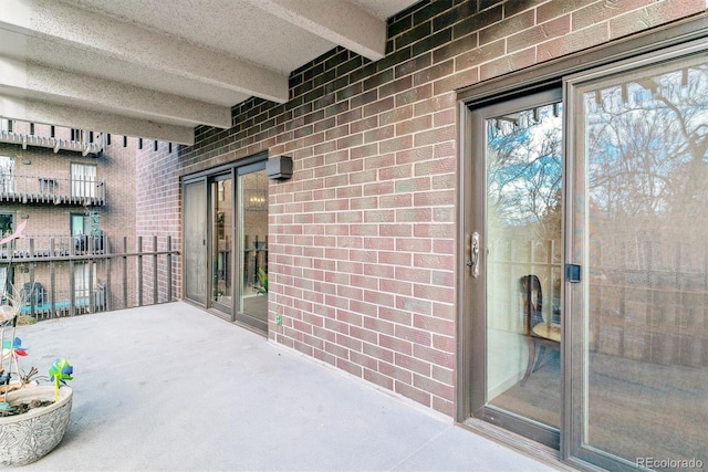 doorway to property featuring brick siding and a balcony