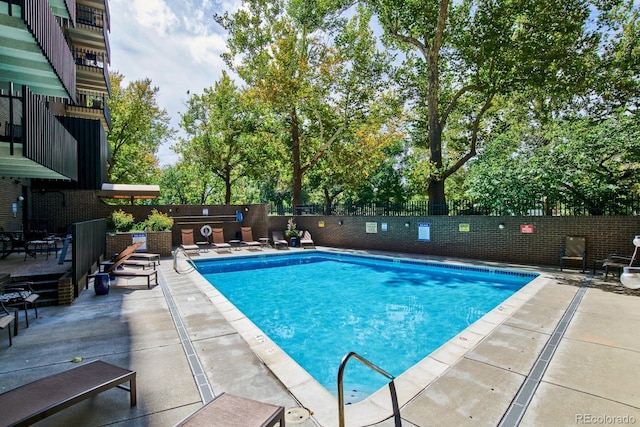 pool with a patio area and fence