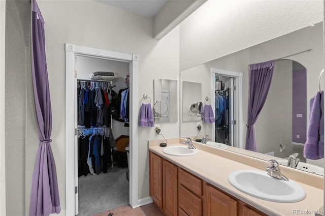 full bath with a walk in closet, a sink, and double vanity