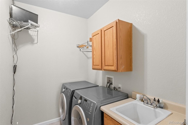 clothes washing area featuring washer and dryer, cabinet space, and a sink