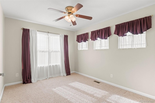 spare room featuring carpet floors, visible vents, baseboards, and a ceiling fan