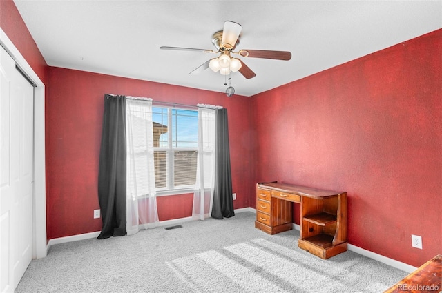 office area with a ceiling fan, light carpet, visible vents, and baseboards