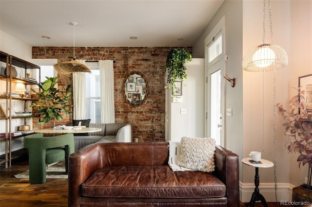 living room with dark wood-type flooring, brick wall, and a baseboard radiator