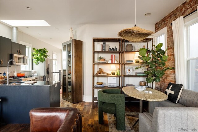 dining space featuring sink, a skylight, dark hardwood / wood-style floors, and brick wall