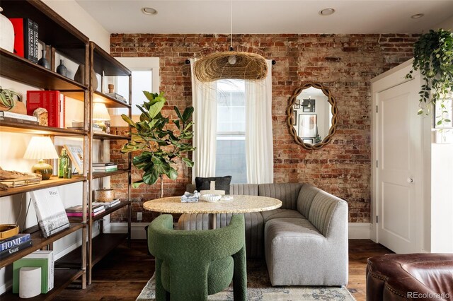 dining space featuring breakfast area, wood-type flooring, and brick wall