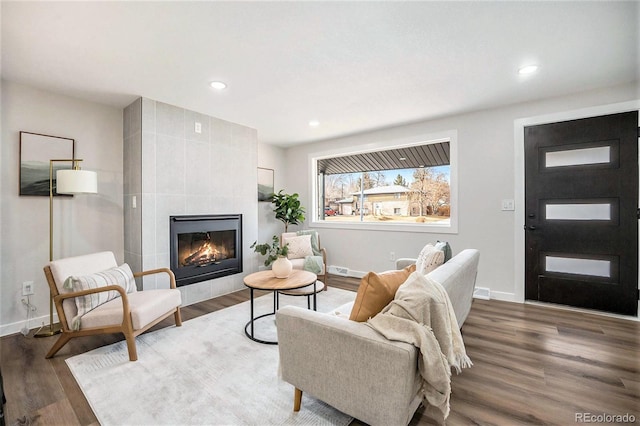 living room with a tiled fireplace and hardwood / wood-style floors