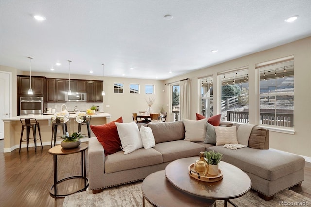 living room featuring recessed lighting, light wood-type flooring, and baseboards