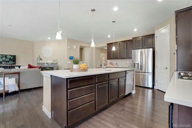 kitchen with a sink, dark brown cabinets, light countertops, appliances with stainless steel finishes, and dark wood-style flooring