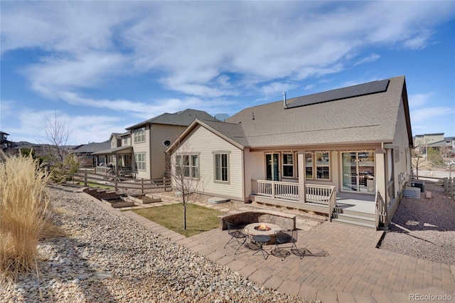 back of house with a patio, a fire pit, and roof mounted solar panels