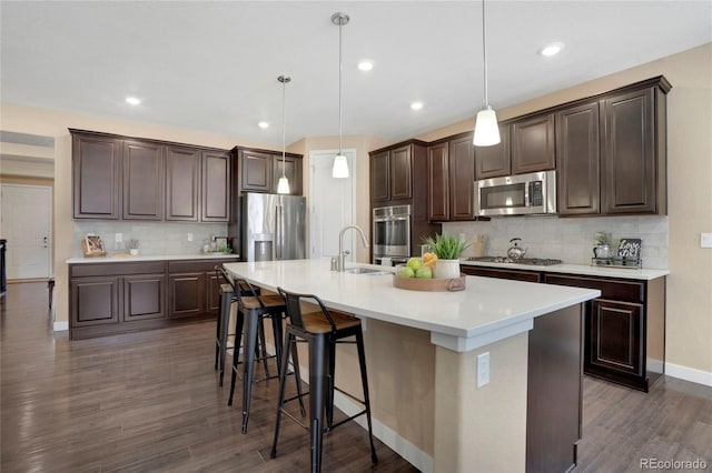 kitchen featuring stainless steel appliances, tasteful backsplash, dark brown cabinets, dark wood-style floors, and recessed lighting