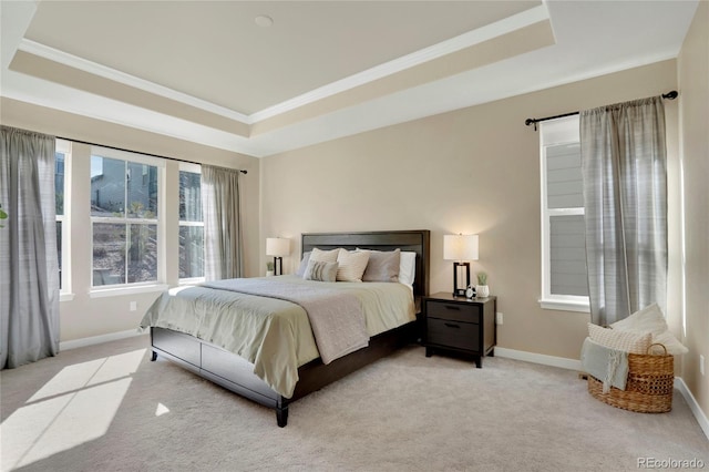 carpeted bedroom with a tray ceiling, ornamental molding, and baseboards
