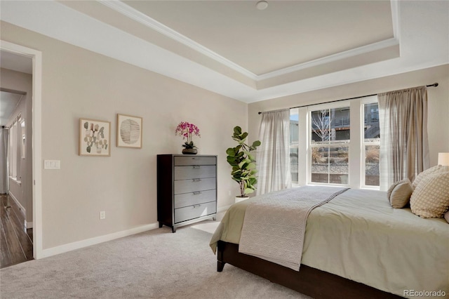 bedroom featuring a tray ceiling, crown molding, light colored carpet, and baseboards