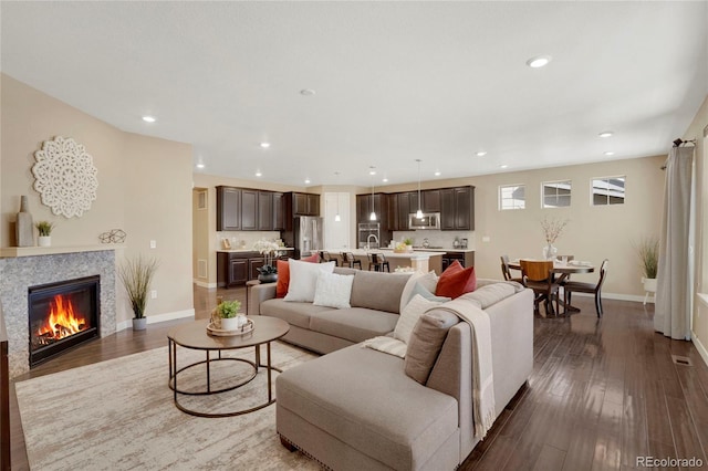 living room featuring wood-type flooring, baseboards, a fireplace, and recessed lighting
