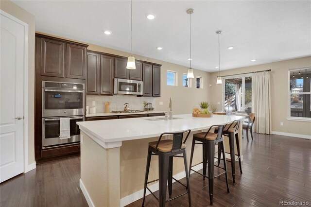9772 Taylor River Cir, Littleton, CO 80125 - kitchen with stainless steel appliances, light countertops, tasteful backsplash, dark wood-type flooring, and dark brown cabinets