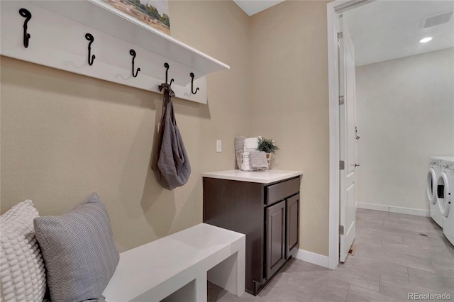 mudroom featuring baseboards, visible vents, and washer and clothes dryer