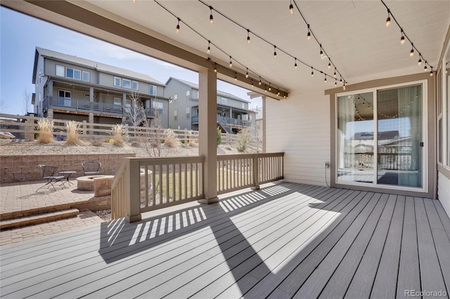 wooden terrace featuring an outdoor fire pit, fence, a patio area, and a residential view