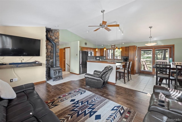 living room with a wood stove, lofted ceiling, ceiling fan, and light hardwood / wood-style flooring