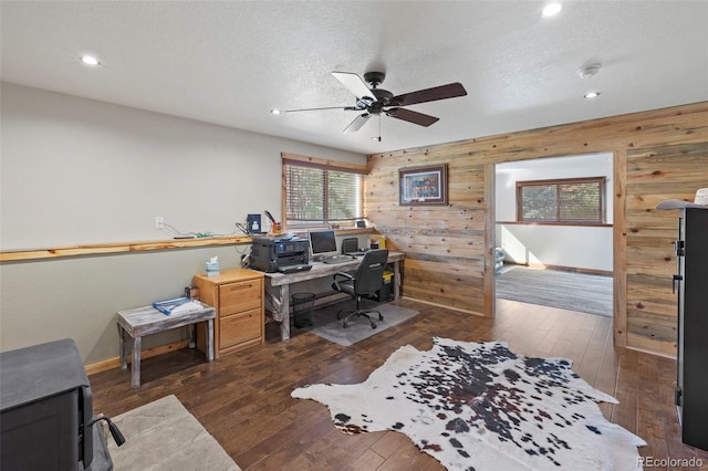 office space featuring dark wood-type flooring, wood walls, a textured ceiling, and ceiling fan