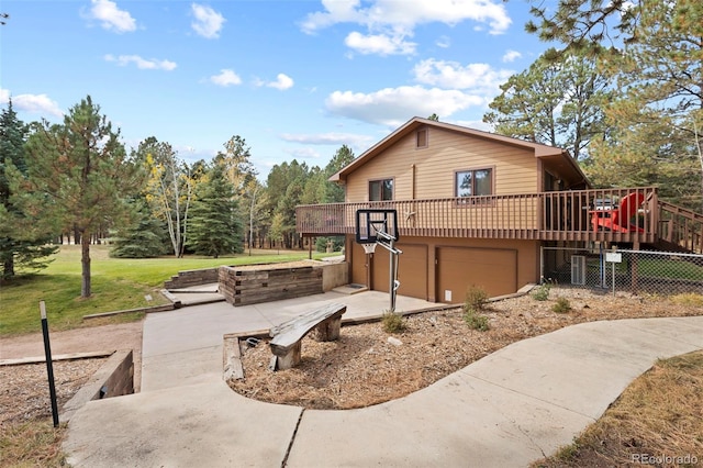 exterior space with a garage, a wooden deck, and a lawn