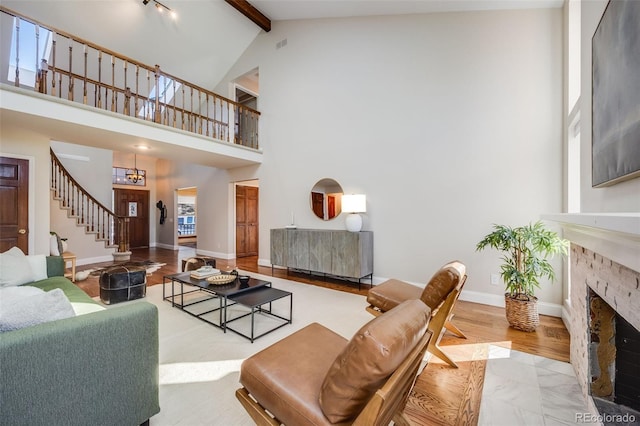 living room featuring high vaulted ceiling, beam ceiling, and a stone fireplace