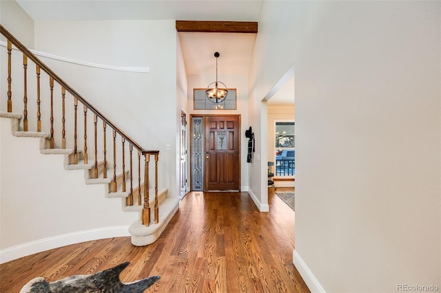 entryway featuring wood-type flooring, a towering ceiling, and an inviting chandelier