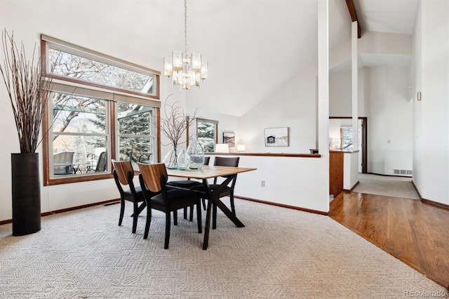 dining area with high vaulted ceiling, light colored carpet, and a notable chandelier