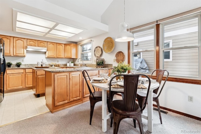 kitchen featuring light carpet, sink, pendant lighting, and stone countertops