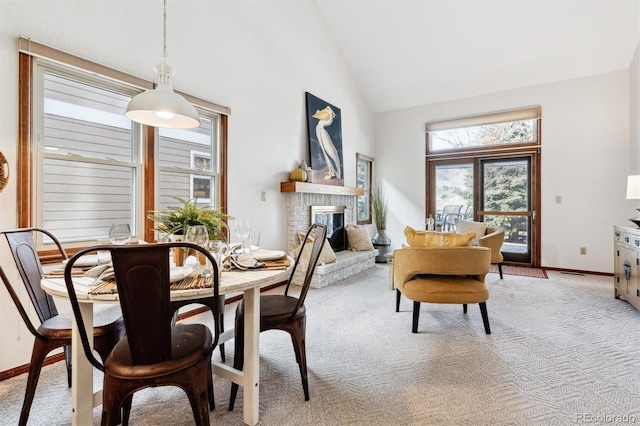 carpeted dining space with high vaulted ceiling and a brick fireplace