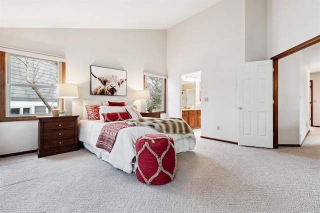 carpeted bedroom featuring ensuite bathroom and high vaulted ceiling